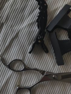 two pairs of scissors sitting on top of a bed next to a pair of shears