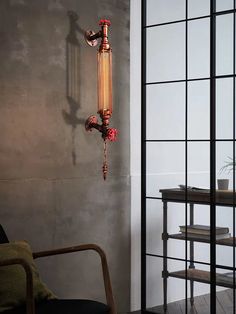 a wall mounted light hanging on the side of a wall next to a chair and table