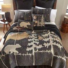 a bed covered in black and white comforter next to a night stand with two lamps