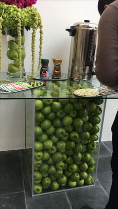 a glass table topped with lots of green apples