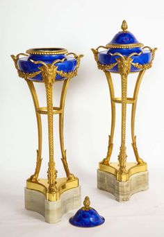 two blue and gold vases sitting next to each other on top of marble bases