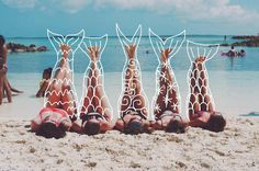 five people laying on their backs in the sand with white lines drawn over them to look like giraffes