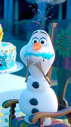 there is a frosted snowman sitting in front of a cake on the table