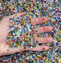 a person's hand with lots of colorful sprinkles all over it