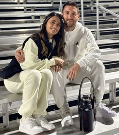 a man and woman sitting on bleachers posing for the camera