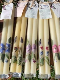 six candles with floral designs on them sitting in the grass