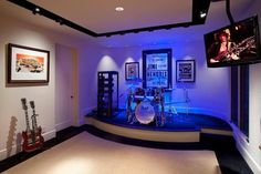 a room that has some guitars and drums on the stage in it with blue lights