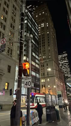 a traffic light sitting on the side of a road next to tall buildings at night