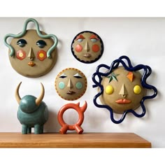 five clay faces are mounted on the wall