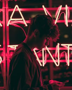 a man looking at his cell phone in front of neon signs