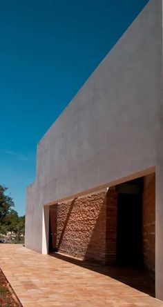 a concrete building with an open door on the outside and brick walls around it, against a blue sky