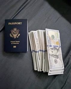 a passport sitting on top of a bed next to stacks of dollar bills in front of it