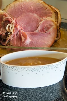 ham and gravy in a white bowl next to a roasting pan