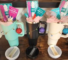 three coffee mugs filled with different types of items on top of a wooden table