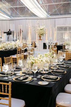 the tables are set with black linens, gold chargers and tall centerpieces