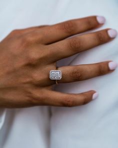 a close up of a person's hand with a diamond ring on their finger