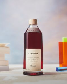 a bottle of wine sitting on top of a table next to some books and pens