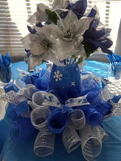 a blue and white centerpiece with flowers in it