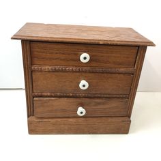 a wooden drawer with three drawers and two white knobs on the bottom one is turned upside down