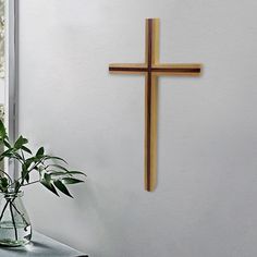 a cross hanging on the wall next to a vase with flowers