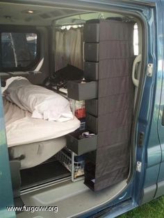 the back door of a blue van with an open bed and storage area in it