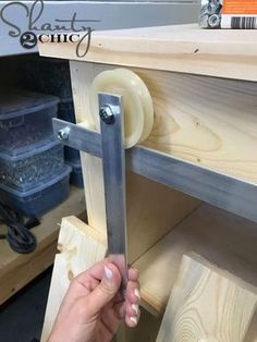 a person is holding a pair of scissors in front of a wooden shelf with drawers