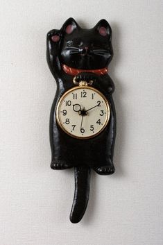 a black cat clock on the wall with it's eyes closed and one eye open