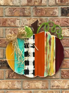 a colorful pumpkin with the word go on it is mounted to a brick wall next to a plant