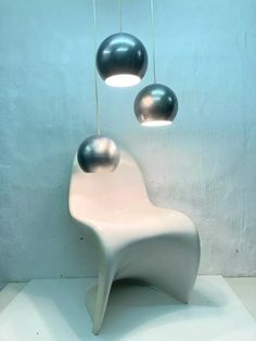 a white chair with three black balls hanging from it