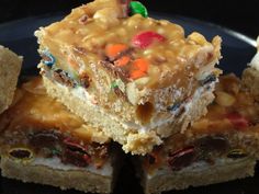 three pieces of cake sitting on top of a black plate with candy bars in the middle