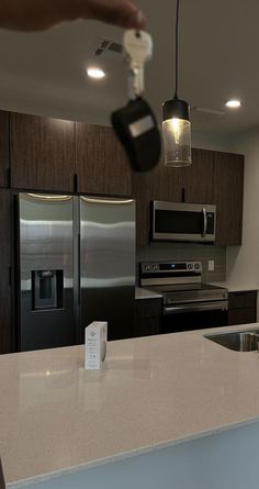 a person is pouring something into a kitchen with stainless steel appliances and dark wood cabinets