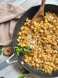 a skillet filled with macaroni and cheese on top of a wooden table