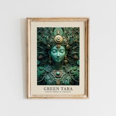 a green tara artwork hangs on the wall in front of a white wall with a gold frame