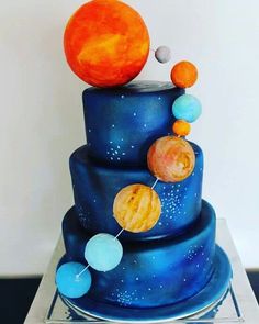 a three tiered blue cake with planets on it