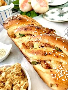 a long loaf of bread sitting on top of a table next to bowls of food