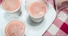 three cups filled with ice cream sitting on top of a white plate next to a red and white checkered table cloth