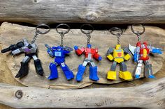 six different colored plastic toy keychains hanging on a piece of drift wood