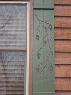 an image of a window with pine cones on the outside and green shutters in front