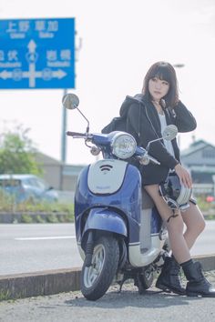 a woman sitting on the back of a scooter next to a street sign