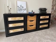 an old typewriter sits on top of a black and wood cabinet with gold drawers