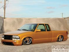 an orange pick up truck parked next to a cement wall