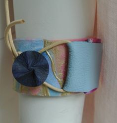 a close up of a cup on a table with a handle and some fabric wrapped around it