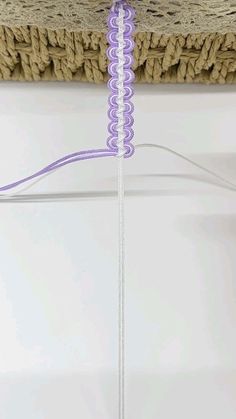 a piece of purple string is hanging from a rafter with a rope attached to it