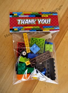 a bag filled with legos sitting on top of a wooden table next to a sign that says thank you