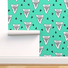 a green wallpaper with black and white triangles on it, next to a roll of toilet paper