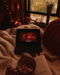 an open book sitting on top of a bed next to a cup of coffee and candle