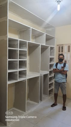 a man is standing in front of shelves that are being built into the wall and put together