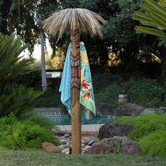 a tiki pole with towels hanging from it's side in a garden area