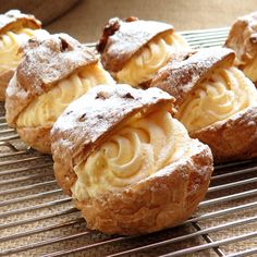 several pastries sitting on a cooling rack with powdered sugar and butter toppings