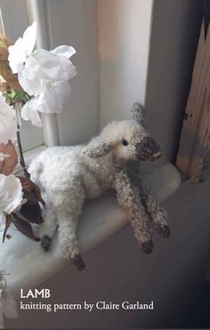 a stuffed lamb sitting on top of a window sill